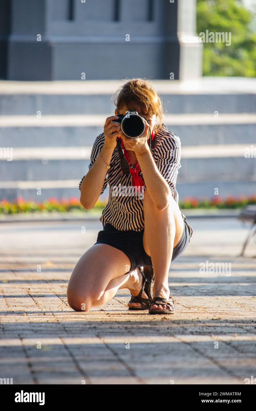 Una bella ragazza fa una foto per strada. Paparazzi con fotocamera. Hobby fotografico. Concetto di reportage su strada. Concetto di business fotografico. Cogli l'attimo Foto Stock