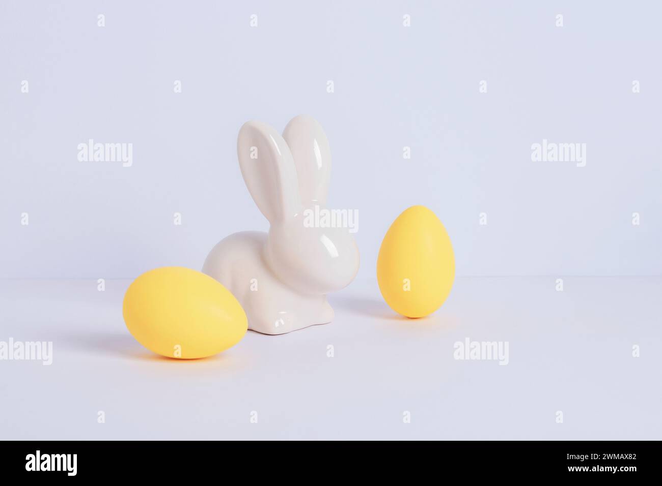 Coniglietto pasquale e due uova gialle su sfondo bianco. Concetto di Pasqua. Primo piano. Foto Stock