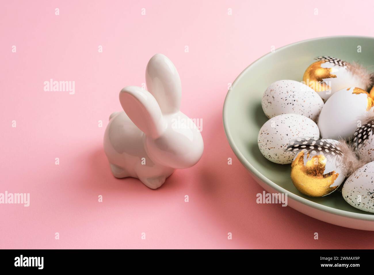 Layout pasquale con piatto di uova di Pasqua e coniglietto sul tavolo rosa. Vista dall'alto. Foto Stock