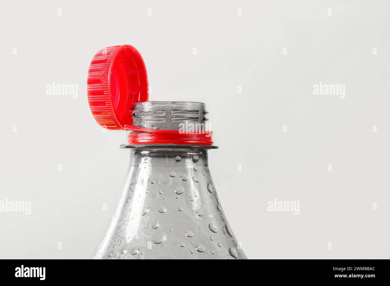 Primo piano del nuovo tappo fissato al flacone in plastica, isolato su sfondo grigio. Concetto di protezione ambientale. Foto Stock