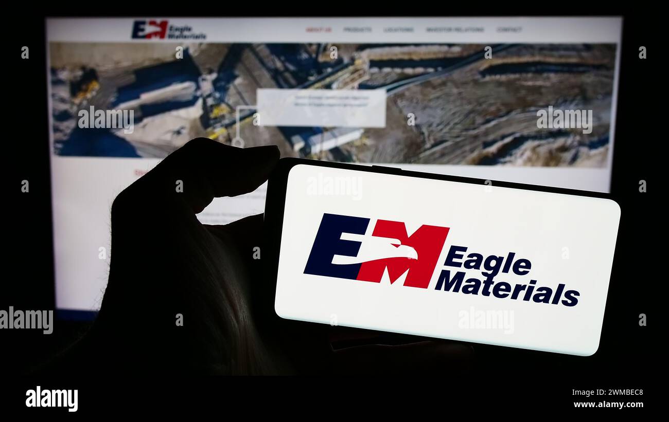 Persona che possiede un telefono cellulare con il logo della società americana di materiali edili Eagle Materials Inc. Di fronte alla pagina Web. Mettere a fuoco il display del telefono. Foto Stock