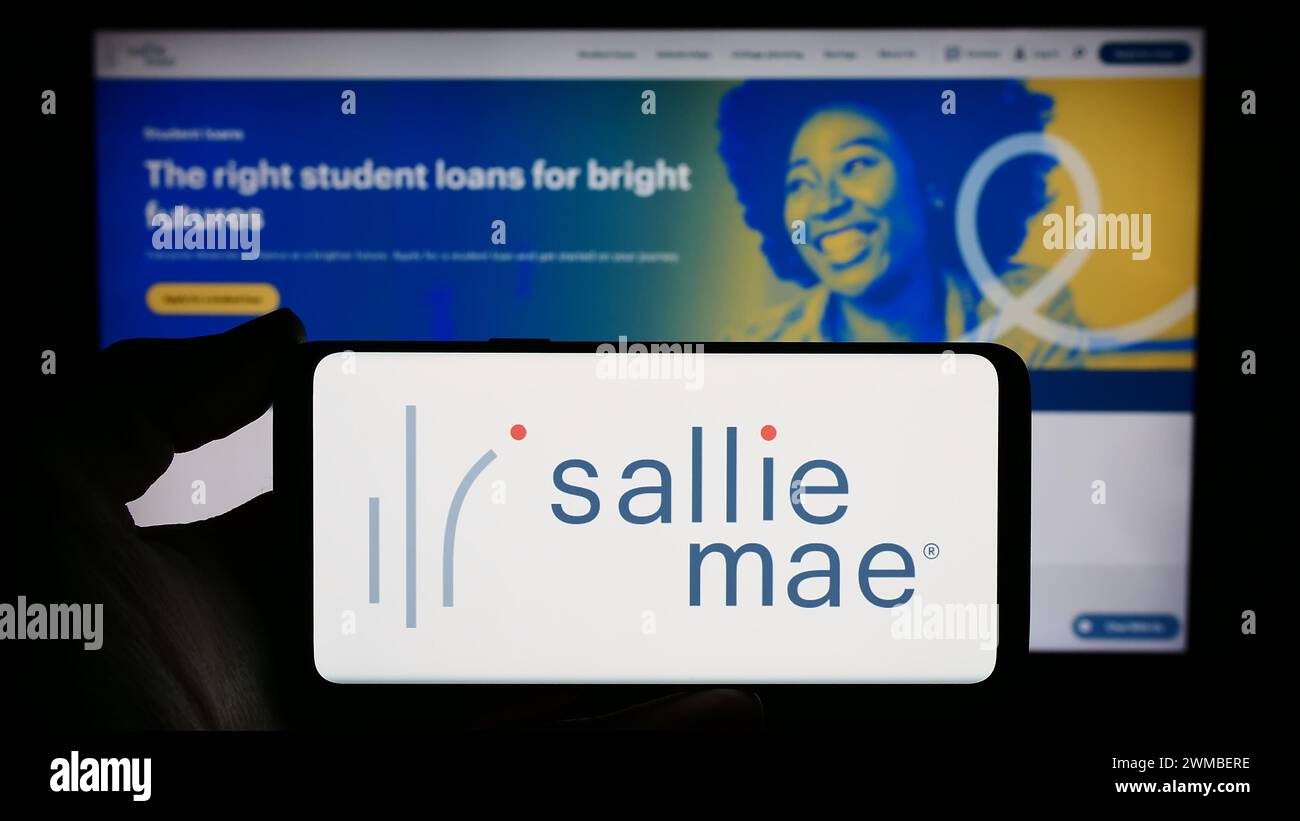 Persona che detiene uno smartphone con il logo della società finanziaria statunitense SLM Corporation (Sallie Mae) davanti al sito web. Mettere a fuoco il display del telefono. Foto Stock