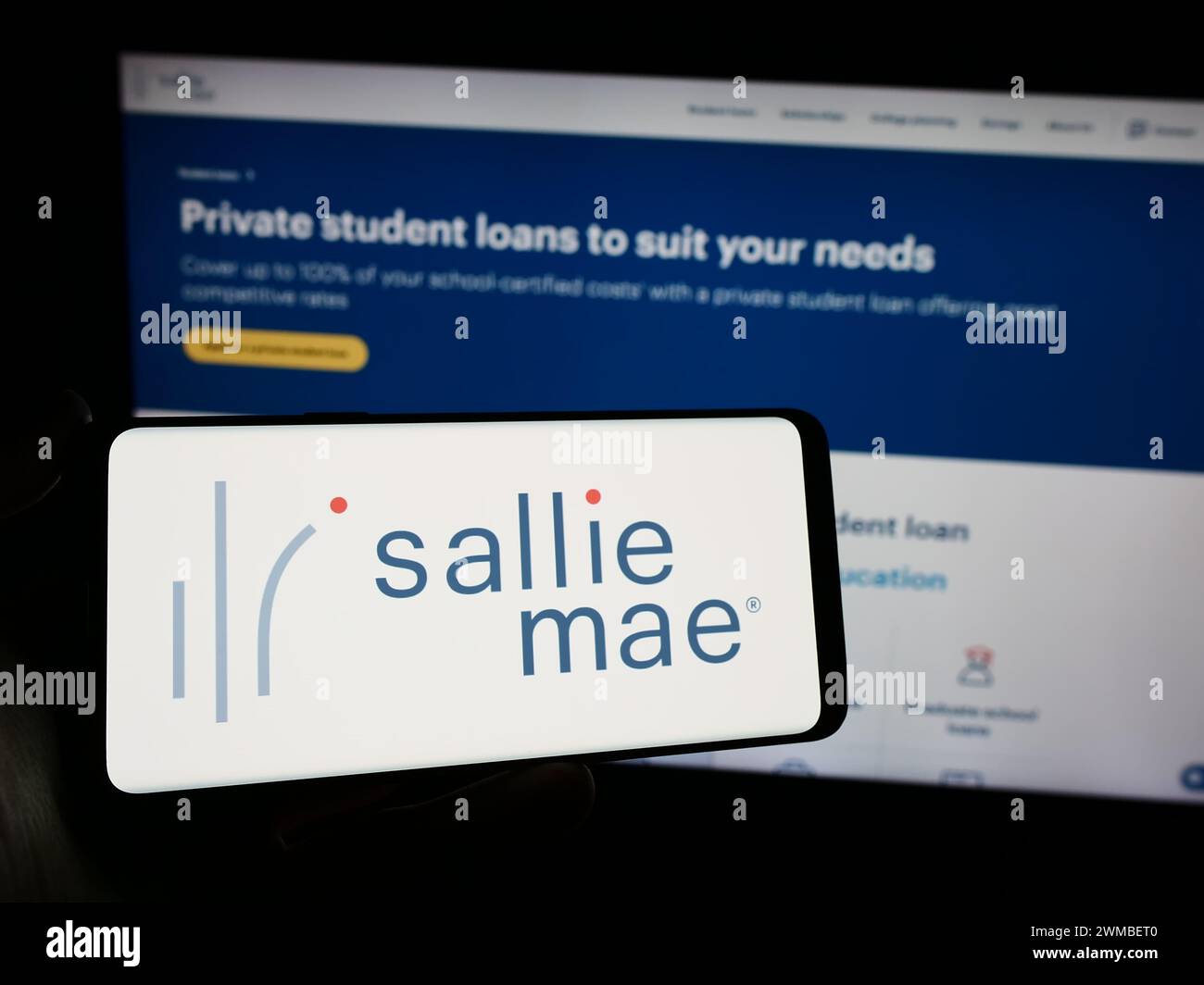 Persona che possiede un telefono cellulare con il logo della società finanziaria americana SLM Corporation (Sallie Mae) davanti alla pagina web. Mettere a fuoco il display del telefono. Foto Stock