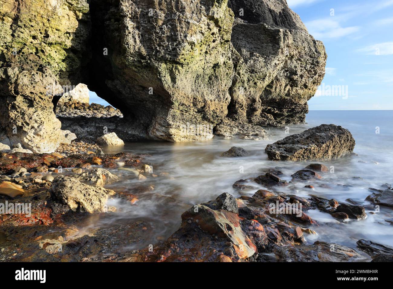 Grotta marina e rocce colorate sulla spiaggia di Seaham Blast, Durham Heritage Coast, Seaham, County Durham, Regno Unito Foto Stock