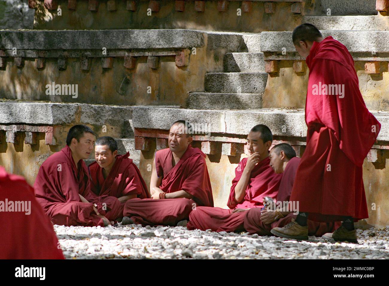 I monaci tibetani possono indossare un'enorme varietà di abiti, cappelli e cappellini spesso in colori tradizionali. Qui ci sono alcuni monaci robed seduti intorno a discutere. Foto Stock