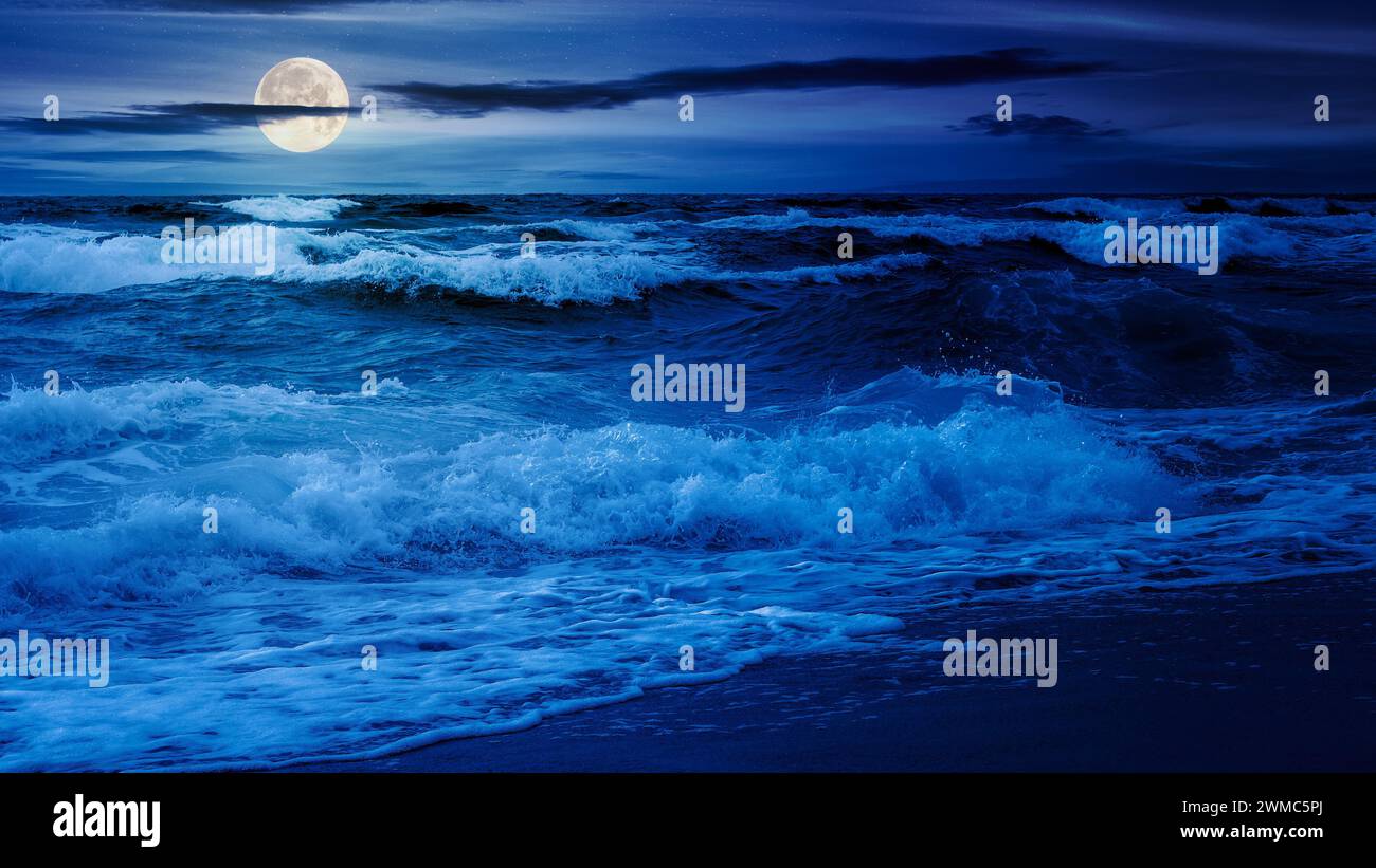 spettacolare paesaggio marino di notte. onde che si infrangono sulla spiaggia alla luce della luna piena Foto Stock