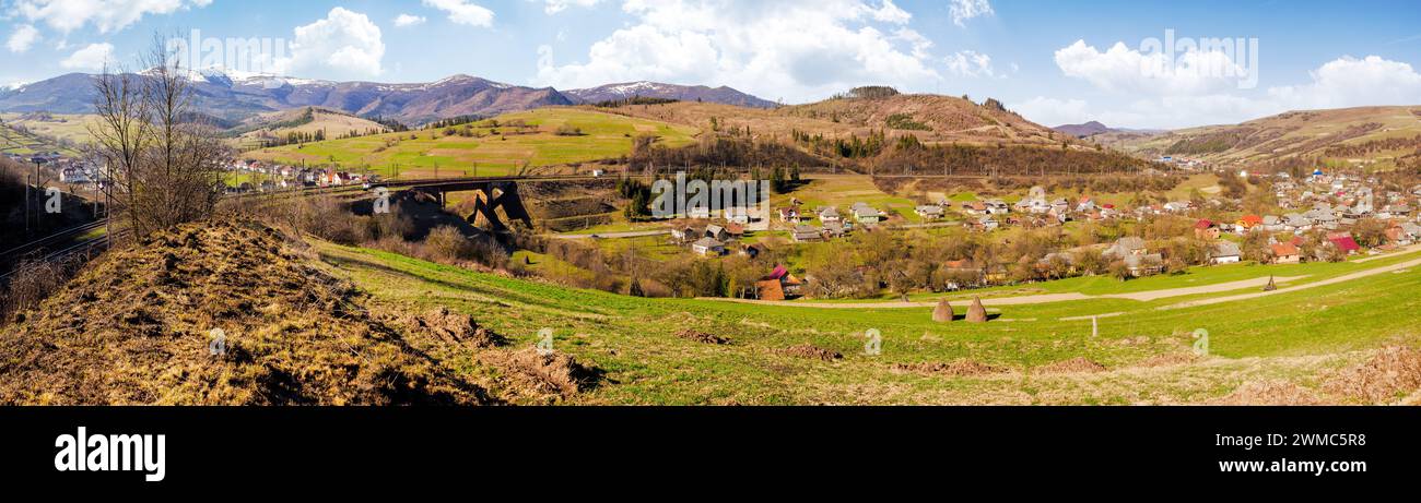 panorama di paesaggio rurale montuoso con villaggio nella valle. paesaggio di campagna dei carpazi con coltivazioni su colline di fronte al crinale borzhava Foto Stock
