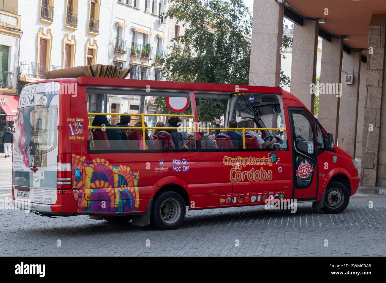 Un minibus Hop-On-Off che porta i turisti in un tour lungo le strade medievali molto più strette nei vecchi quartieri della storica città di Cordova in Anda Foto Stock