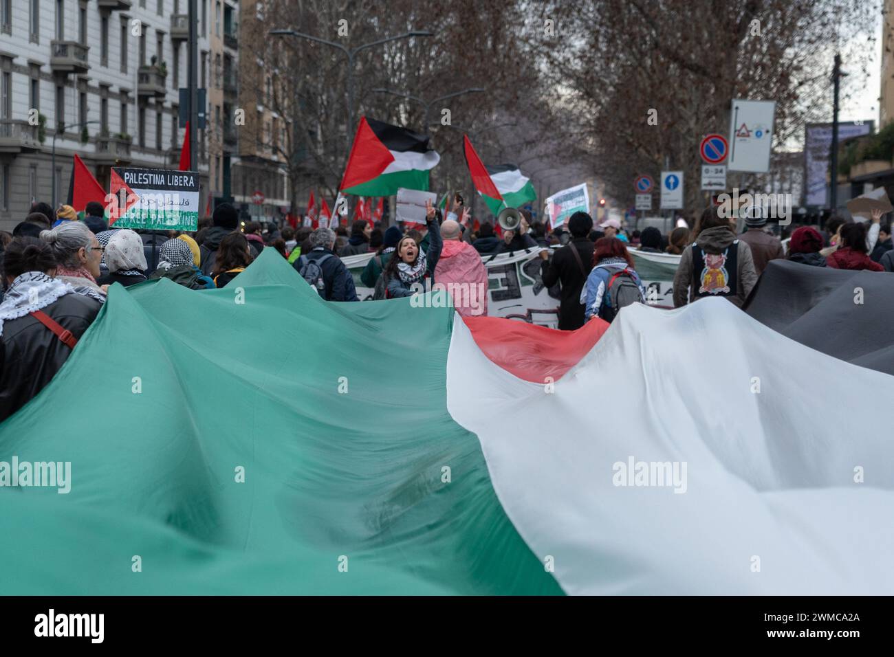 I manifestanti marciano mentre detengono una grande bandiera palestinese durante una manifestazione pro-Palestina. Foto Stock