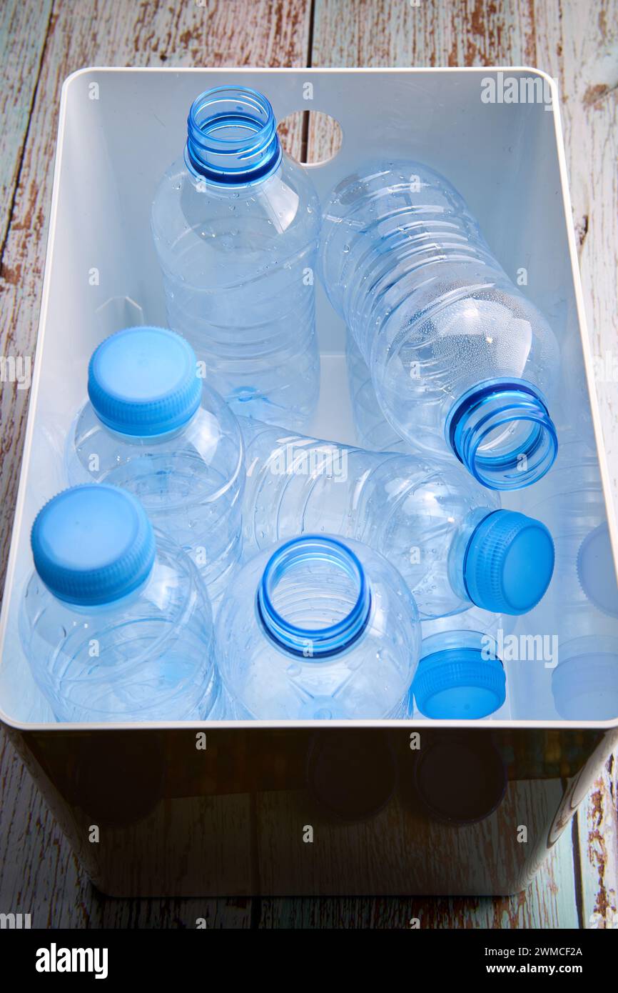 Vista dall'alto dei flaconi di plastica chiusi e aperti posti in un contenitore bianco dopo il riciclaggio per il riutilizzo Foto Stock