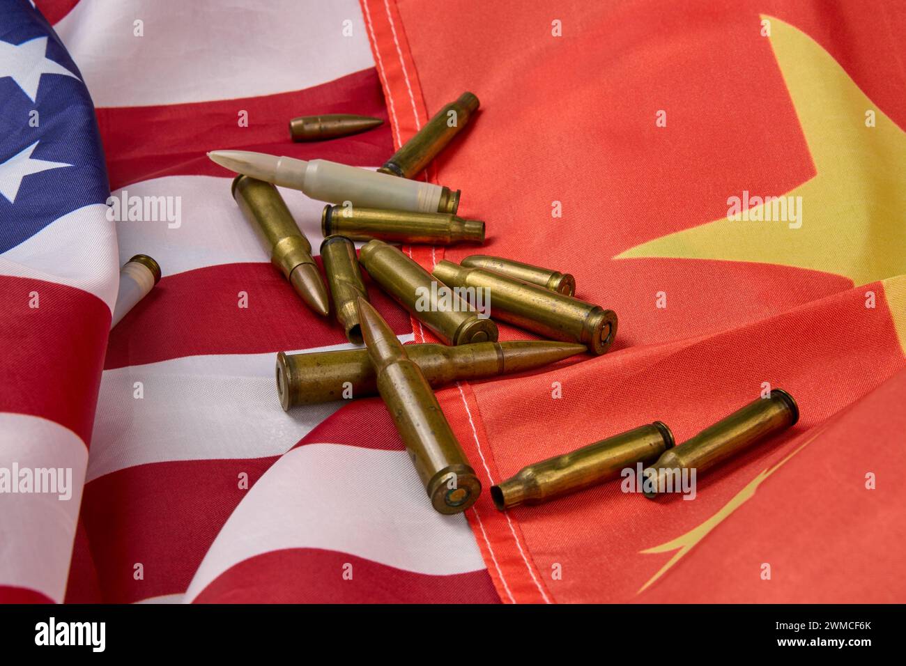 Primo piano di cartucce e proiettili di diverse dimensioni disposti sopra la bandiera americana e cinese. Foto Stock