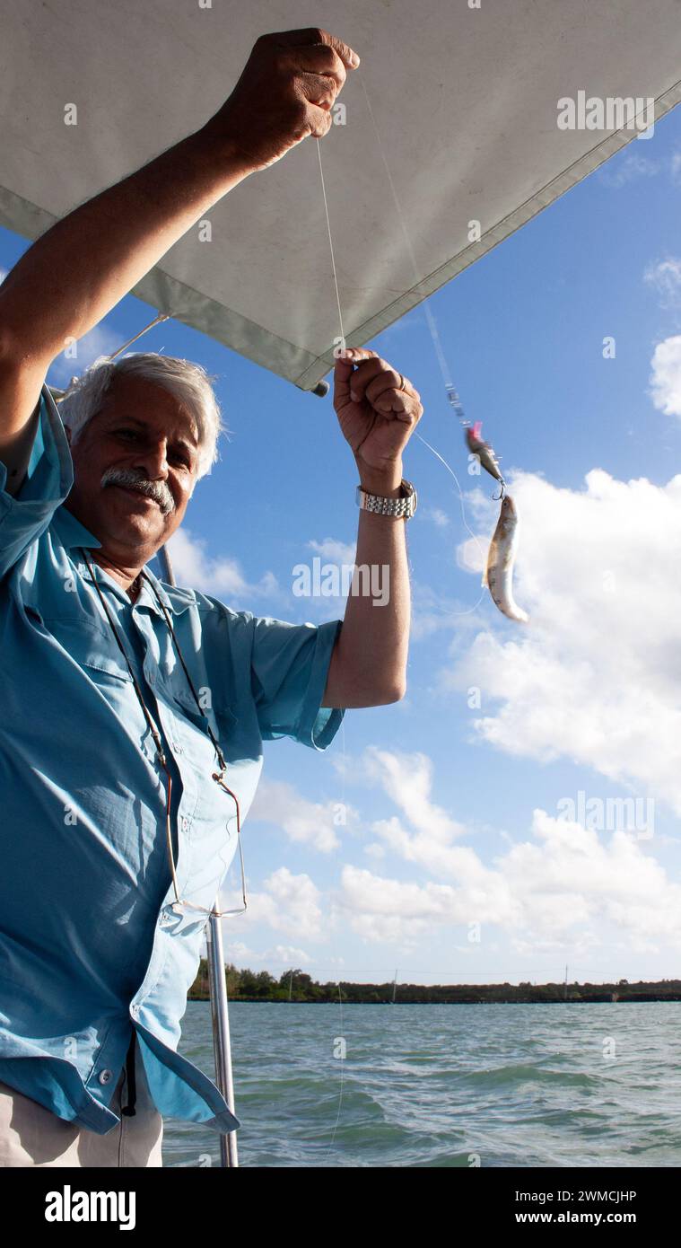 Sorridente uomo anziano in piedi su una barca a pescare, Mauritius Foto Stock