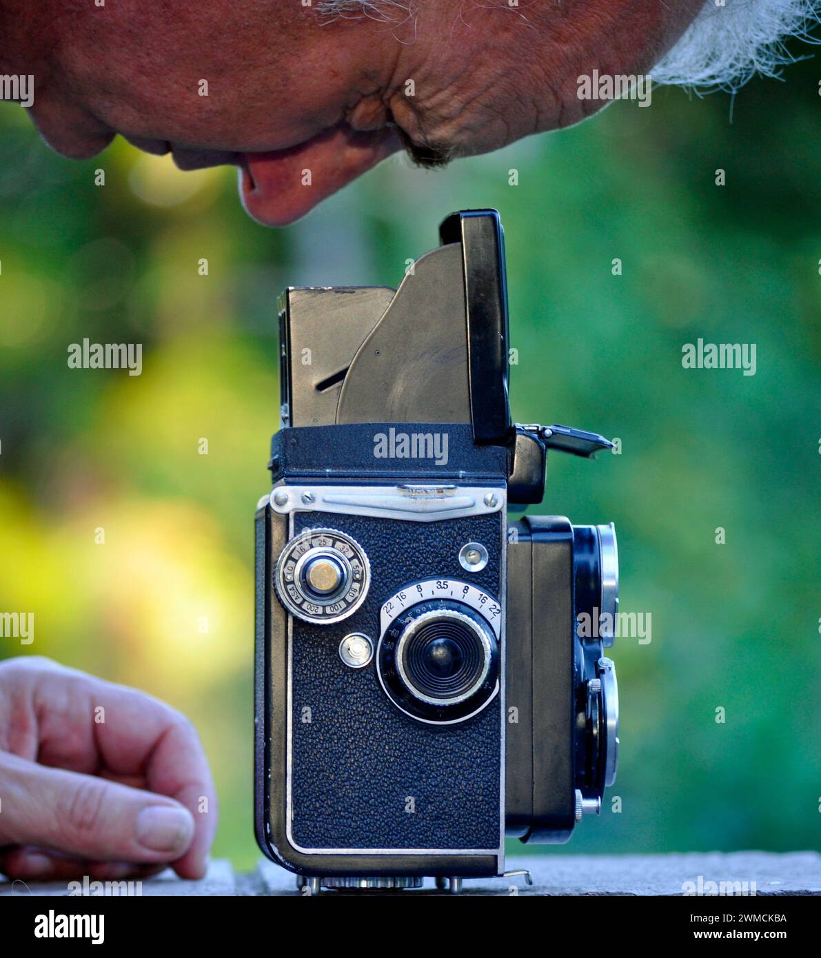 Primo piano di un uomo che guarda nel mirino di una fotocamera vintage di formato medio Foto Stock
