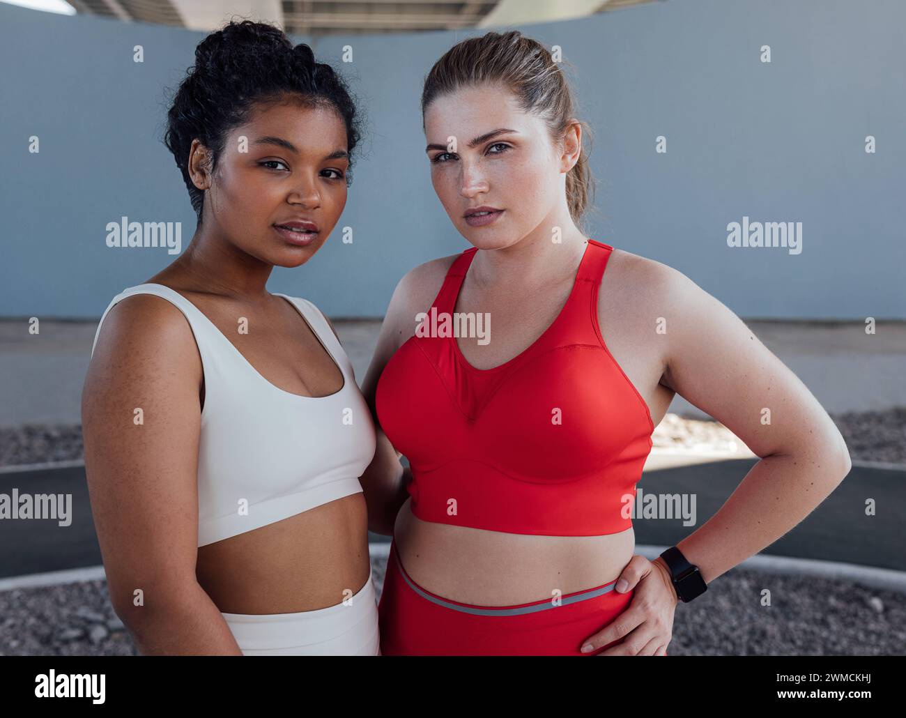 Ritratto di due giovani donne più grandi in abbigliamento sportivo. Due donne di diverse etnie stanno insieme dopo l'allenamento all'aperto. Ritratto di due anni Foto Stock
