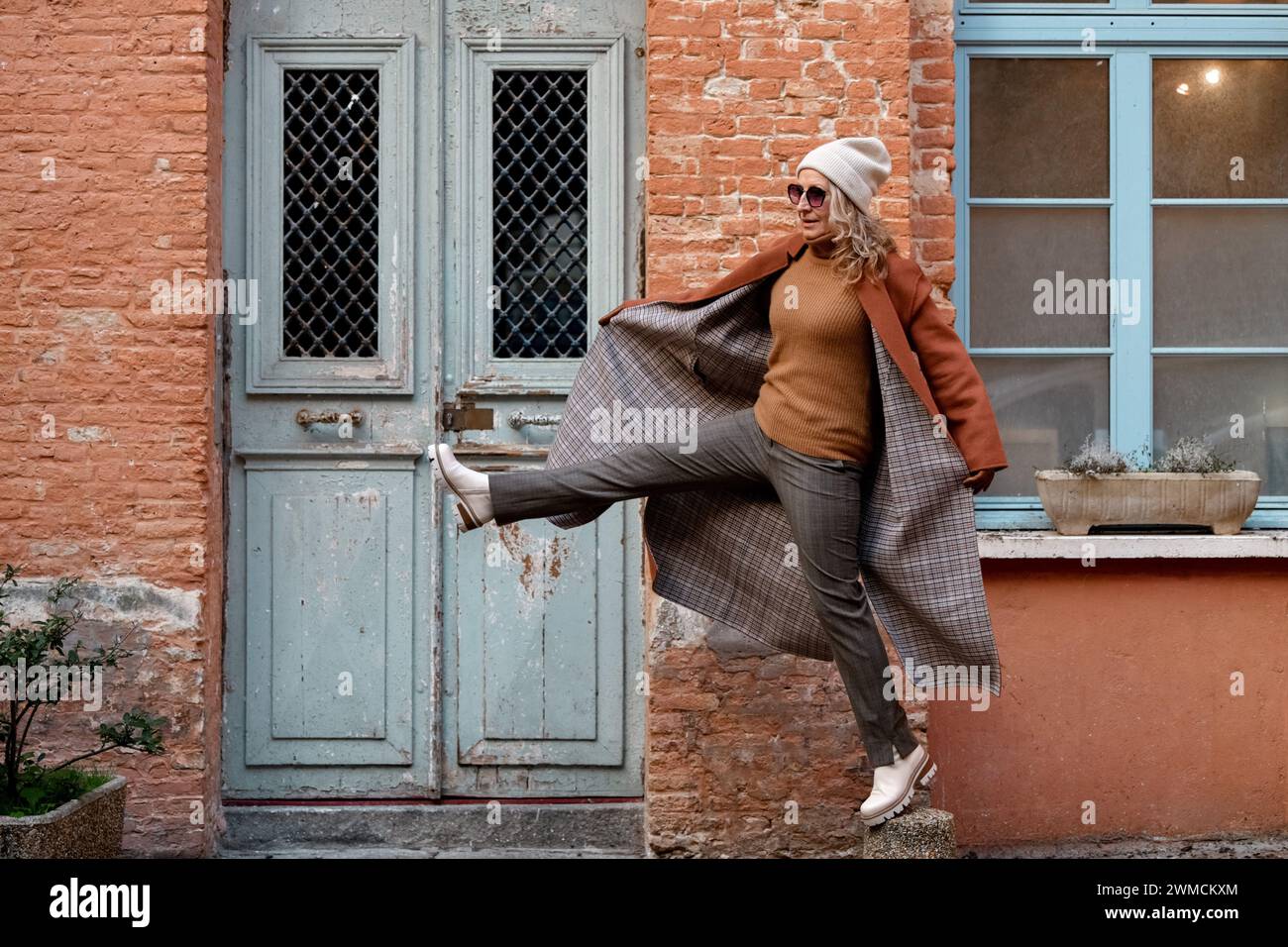 Una donna con cappotto in terracotta e guanti in pelle in città Foto Stock