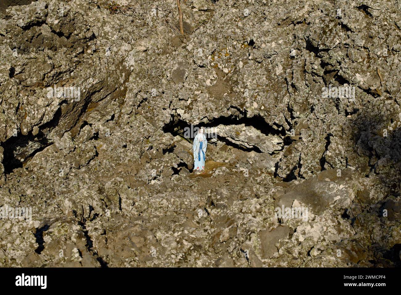 Statua di nostra Signora di Lourdes tra la roccia lavica del Parco dell'Etna, Sicilia, Italia Foto Stock