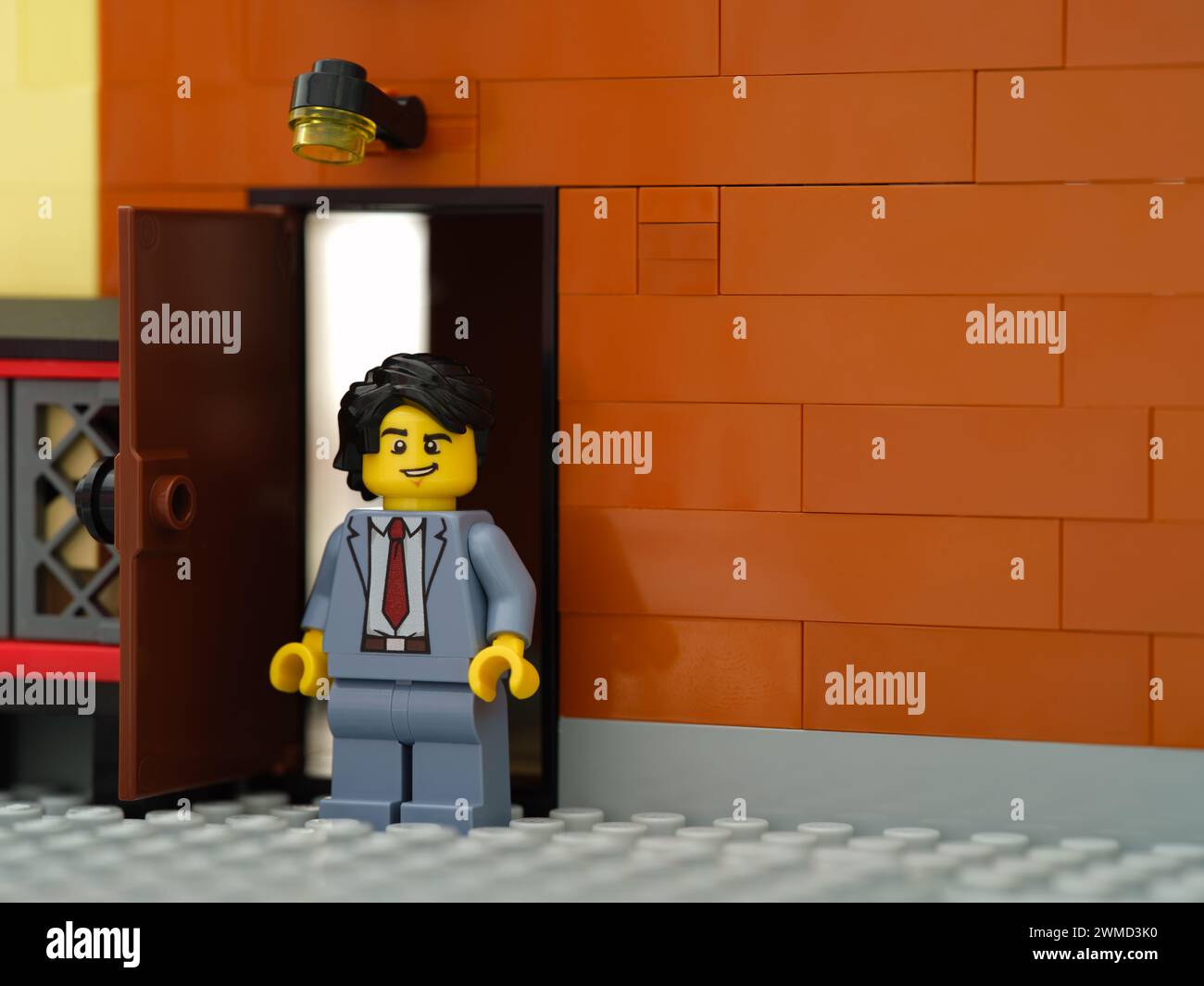 Tambov, Federazione Russa - 17 febbraio 2024 Una minifigura d'affari Lego in piedi dietro un edificio vicino a una porta aperta Foto Stock