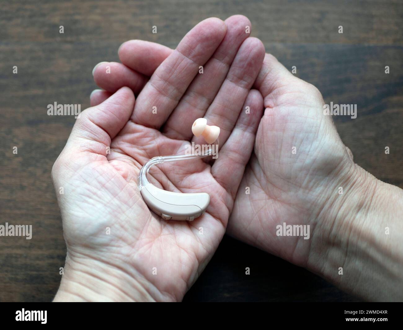 Apparecchio acustico per mani, piccolo dispositivo elettronico indossabile dietro l'orecchio, messa a fuoco selettiva. Giornata mondiale dell'udito Foto Stock