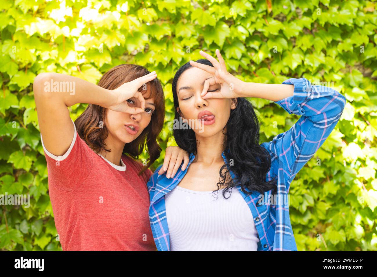 Le amiche birazziali fanno gesti giocosi all'aperto Foto Stock