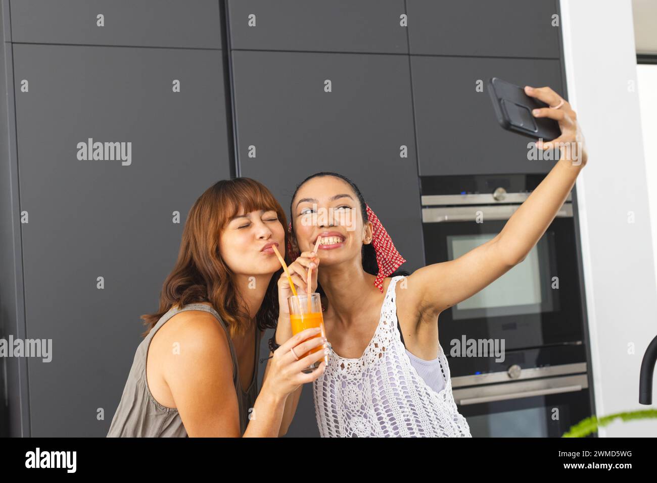 Due giovani donne birazziali fanno un selfie giocoso a casa Foto Stock