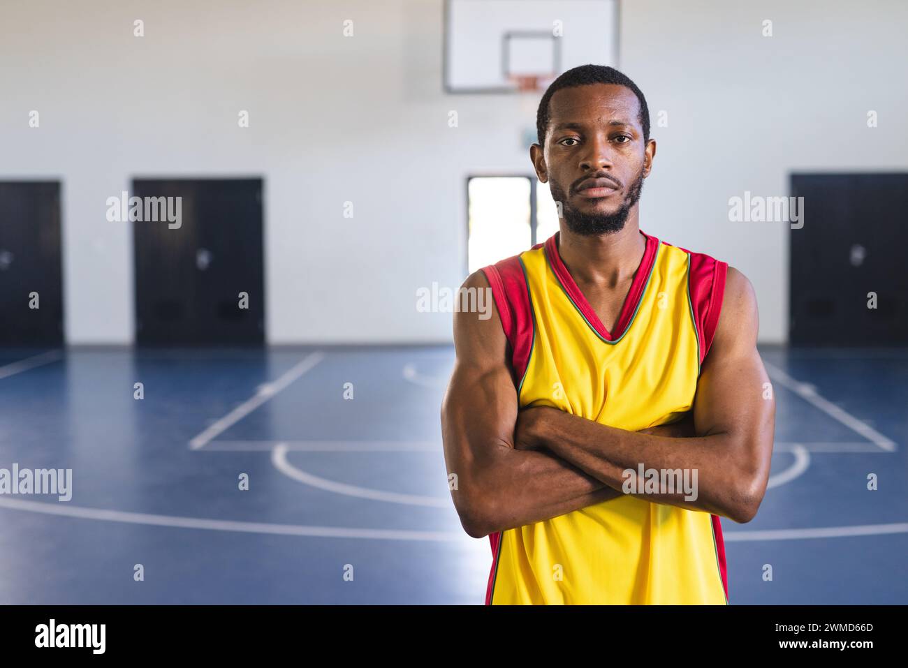 Un uomo afroamericano sta in piedi con fiducia su un campo da basket Foto Stock