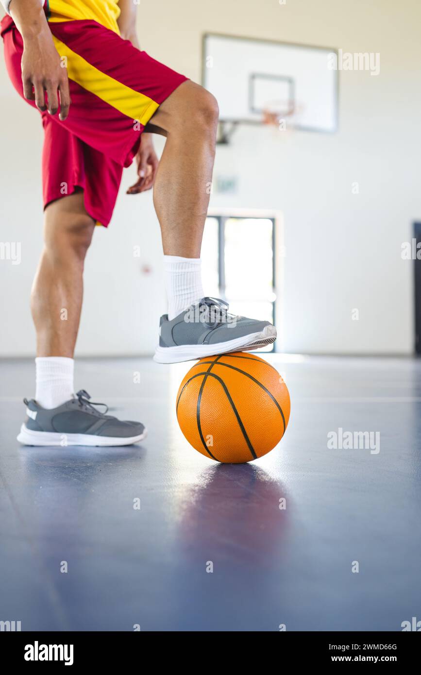 Il giovane uomo birazziale si prepara a giocare a basket al chiuso, con spazio di copia Foto Stock