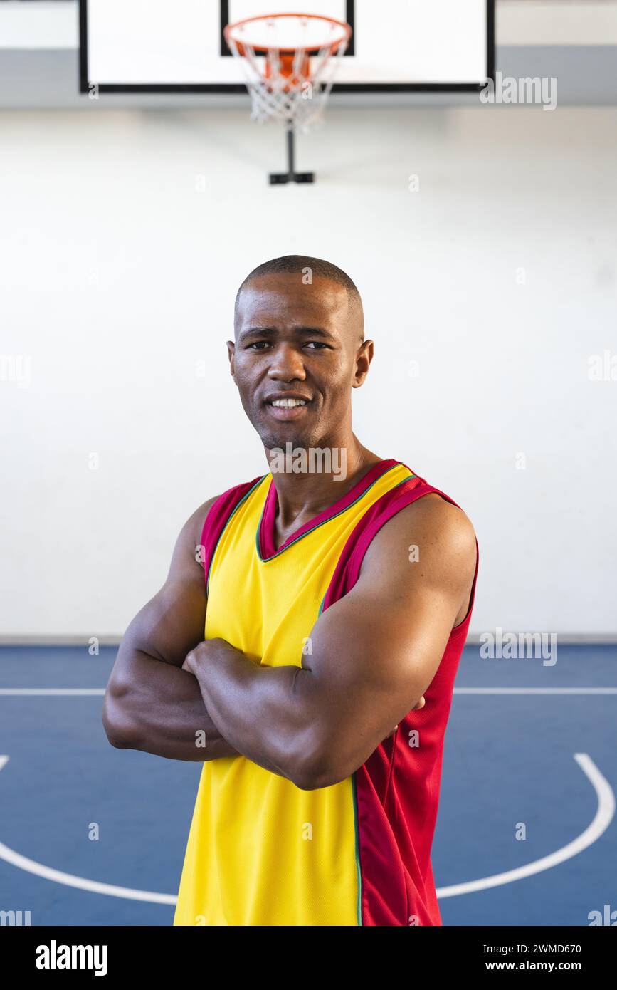Un uomo afroamericano fiducioso posa in un campo da basket Foto Stock