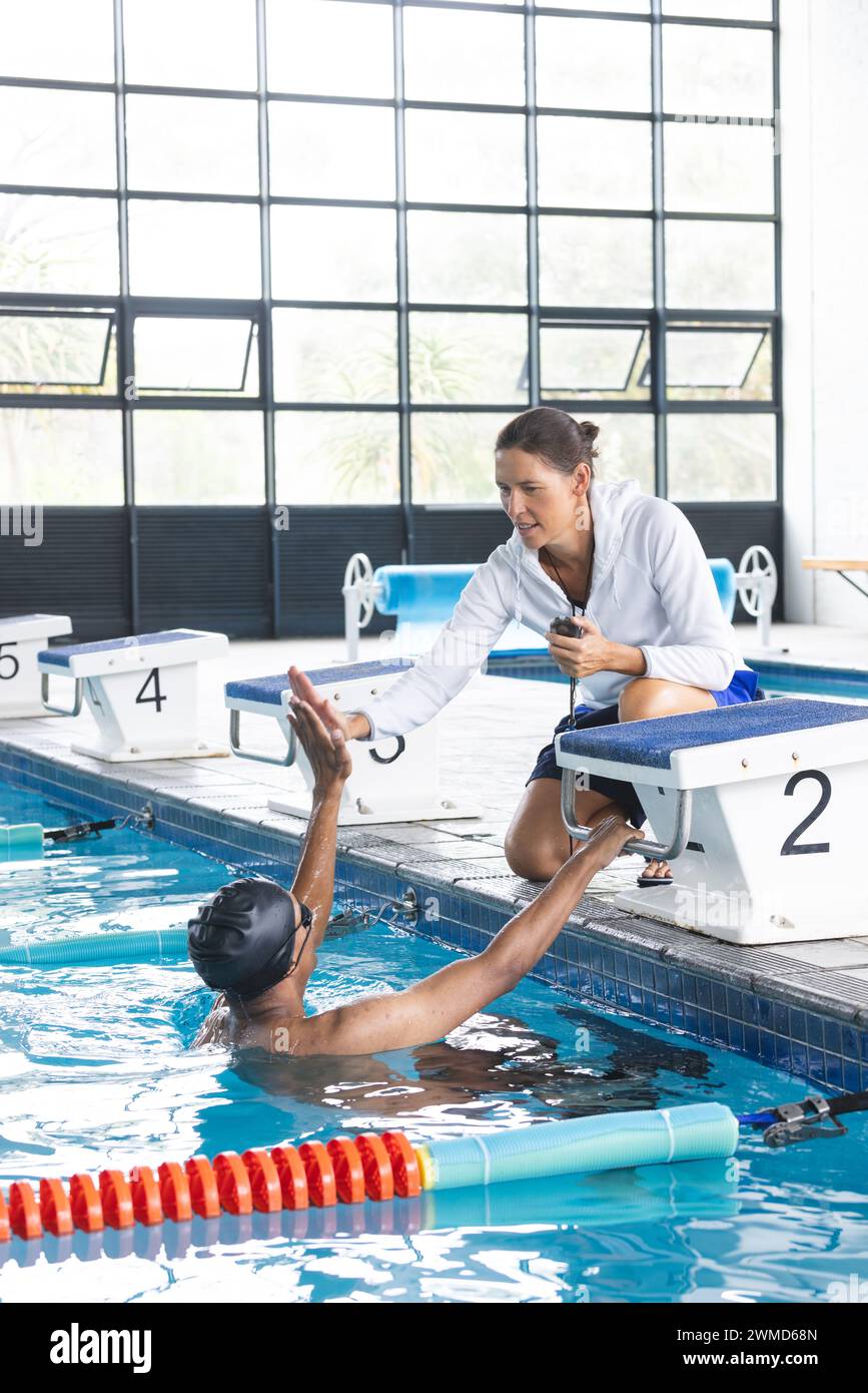 Il pullman incoraggia un nuotatore in una piscina coperta, con spazio per fotocopie Foto Stock