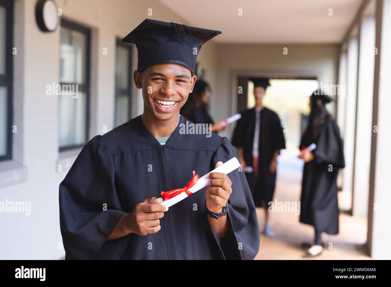 Beaming laureato tiene il suo diploma al liceo Foto Stock