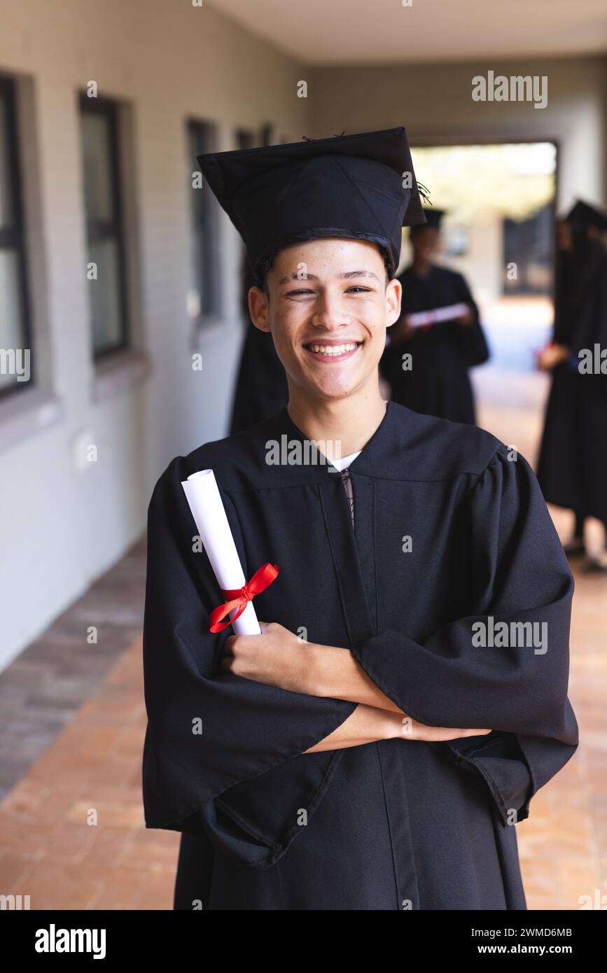 Fiero ragazzo birazziale adolescente in abito da laurea Foto Stock