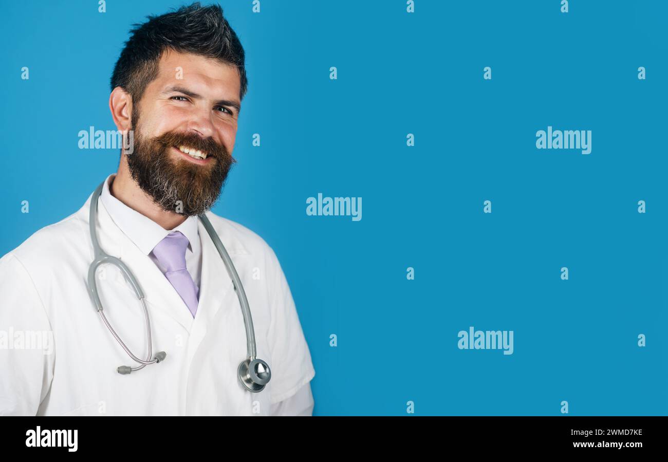 Medico sorridente o medico in cappotto medico bianco con stetoscopio. Servizi di trattamento, assistenza sanitaria, medicina e ambulanza. Uomo barbuto in medico Foto Stock