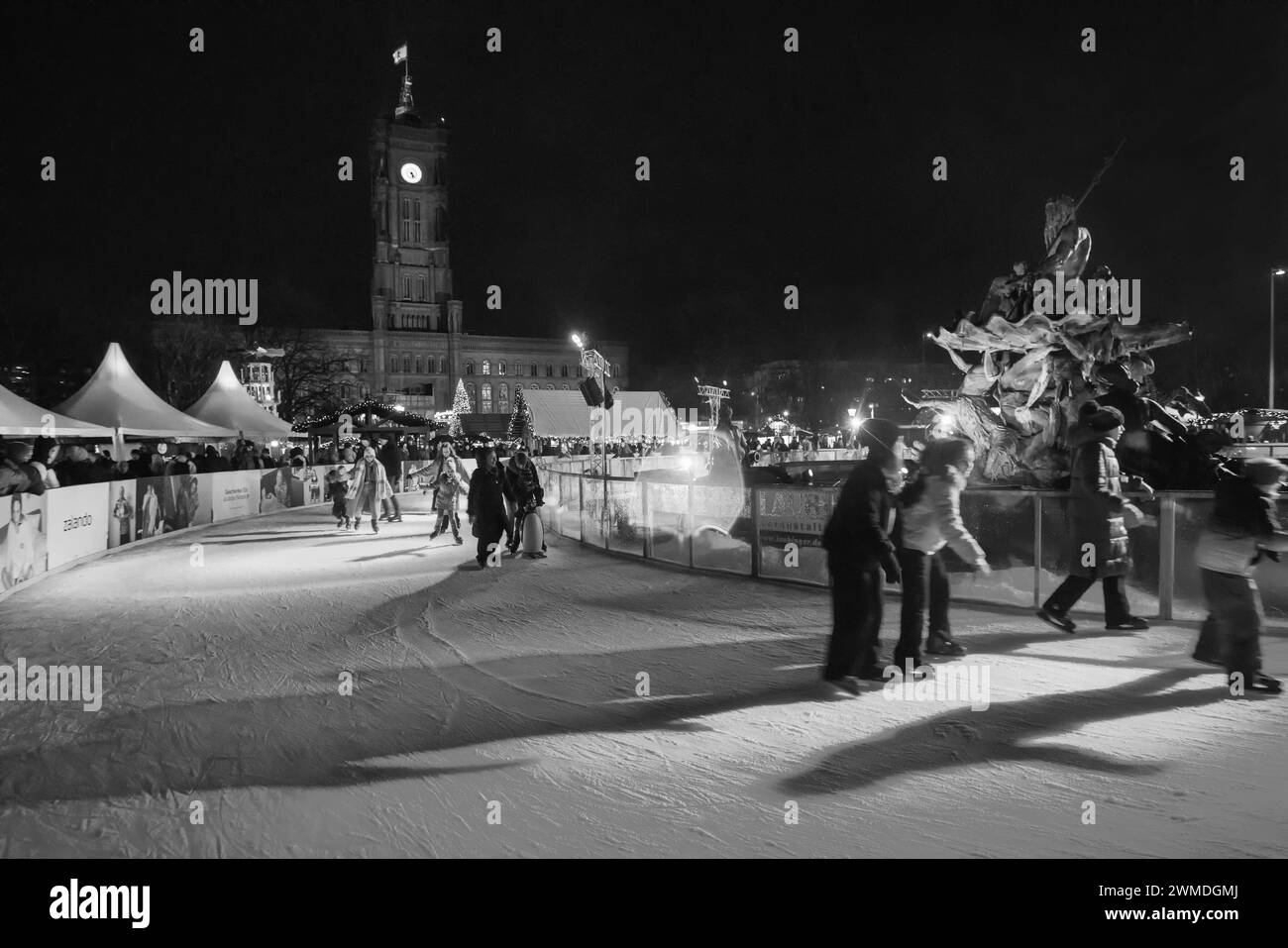 12-23-2023 Berlino giovani sulla pista di pattinaggio sul ghiaccio nel centro di Berlino e sulla torre dell'orologio Rotes Rathaus. Le spie rosse (rosa) illuminano persone e ghiaccio Foto Stock