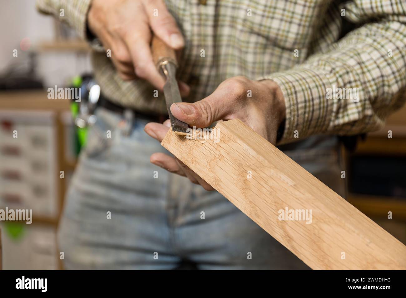 Artigiano con foto orizzontale che usa uno scalpello per intagliare a mano un pezzo di legno, mostrando l'abilità della lavorazione del legno tradizionale. Business co Foto Stock