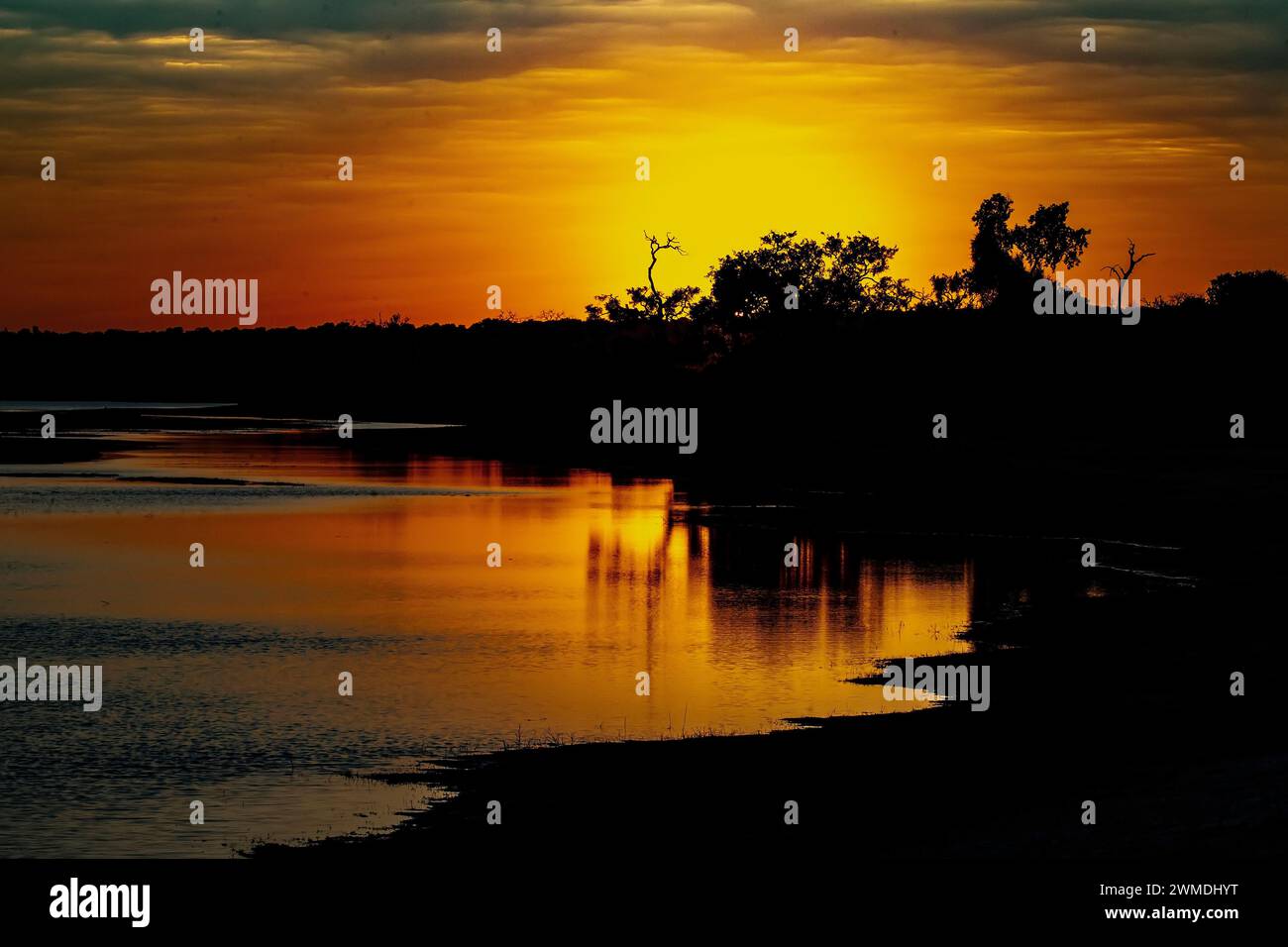 Un tramonto africano sul fiume Chobe in Botswana con acque calme e piatte Foto Stock