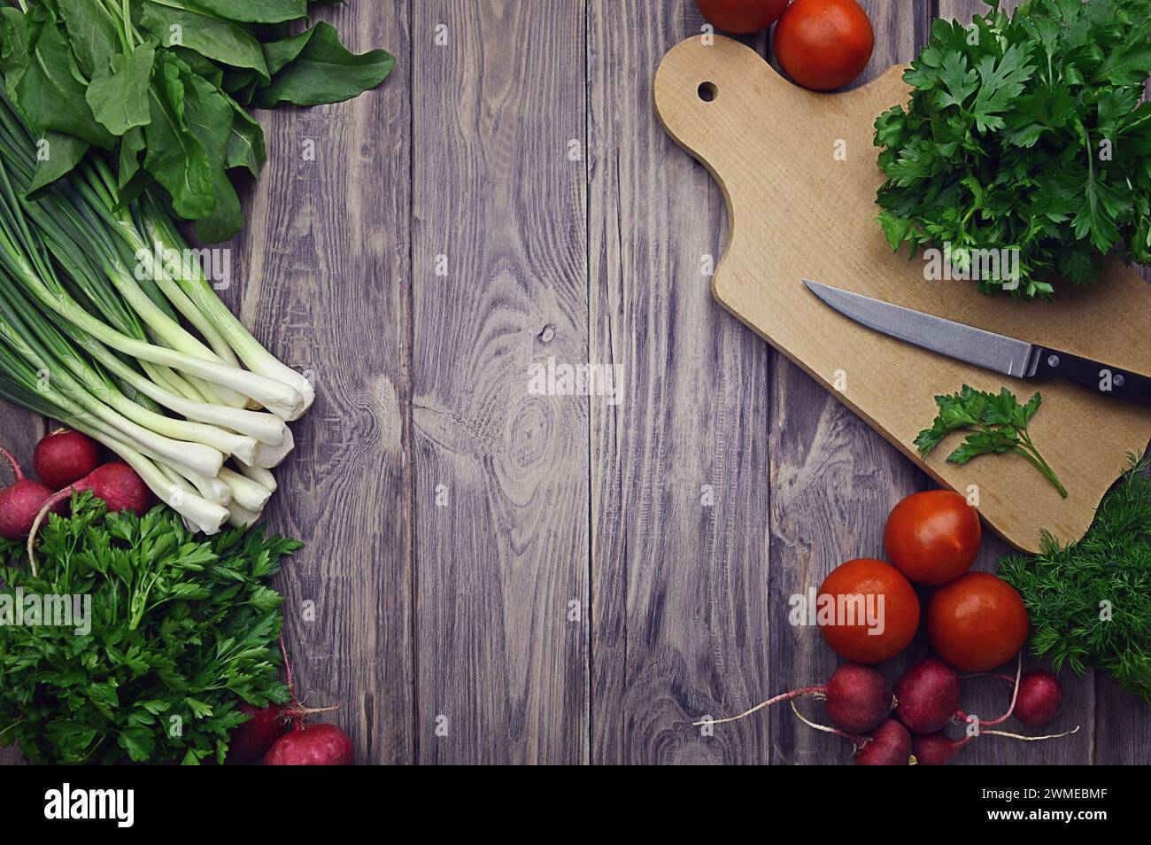 Verdure fresche. Dieta. Mangiare sano pomodori, ravanelli, cipolle verdi, spinaci, prezzemolo, aneto, coriandolo, aglio su fondo di legno. Eati sani Foto Stock