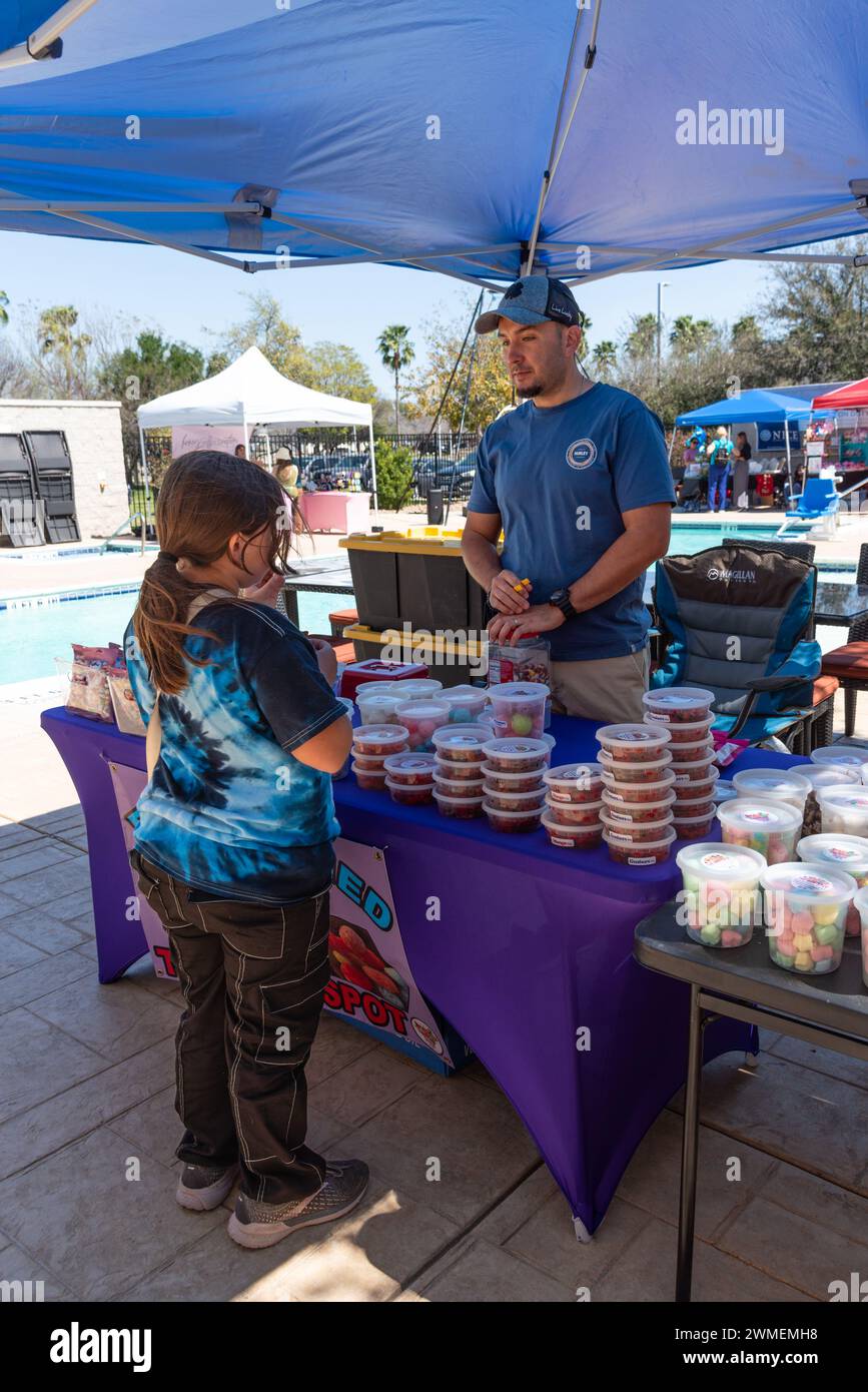 Uomo allo stand del venditore che vende caramelle con un cliente, una giovane ragazza, al South Texas Irish Festival, McAllen, Texas, USA. Foto Stock