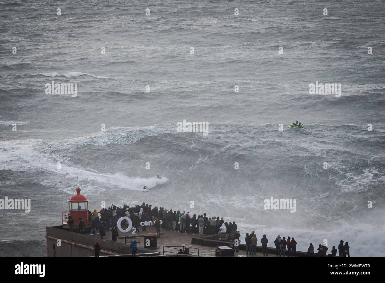 Le persone in cima al faro di Nazaré osservano un surfista che cattura un'onda gigante. Venerdì 23 e sabato 24 febbraio, la spiaggia portoghese di Praia do Norte a Nazaré è stata colpita da una violenta tempesta che ha creato onde giganti per le quali questo luogo è famoso in tutto il mondo. Le condizioni meteorologiche epiche hanno creato onde alte oltre 20 metri. Credito: SOPA Images Limited/Alamy Live News Foto Stock