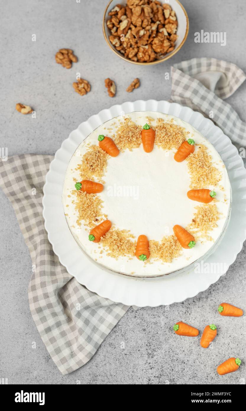 Torta di carote fatta in casa con noci, ghiacciata con formaggio spalmabile. Dolce dolce. Piatto con deliziosa torta di carote Foto Stock