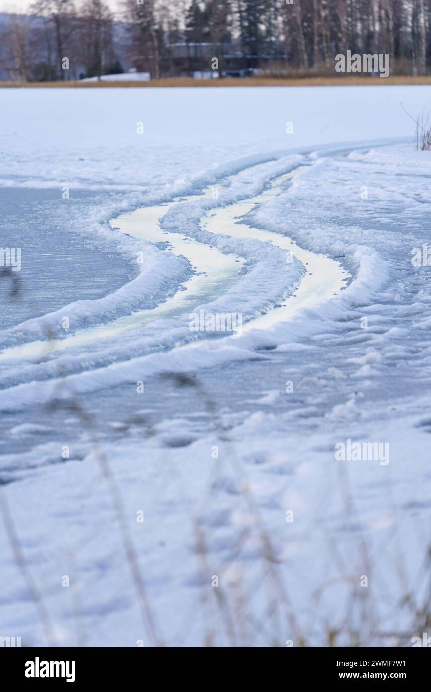 Tracce di pneumatici bagnate su un lago ghiacciato, primo piano Foto Stock