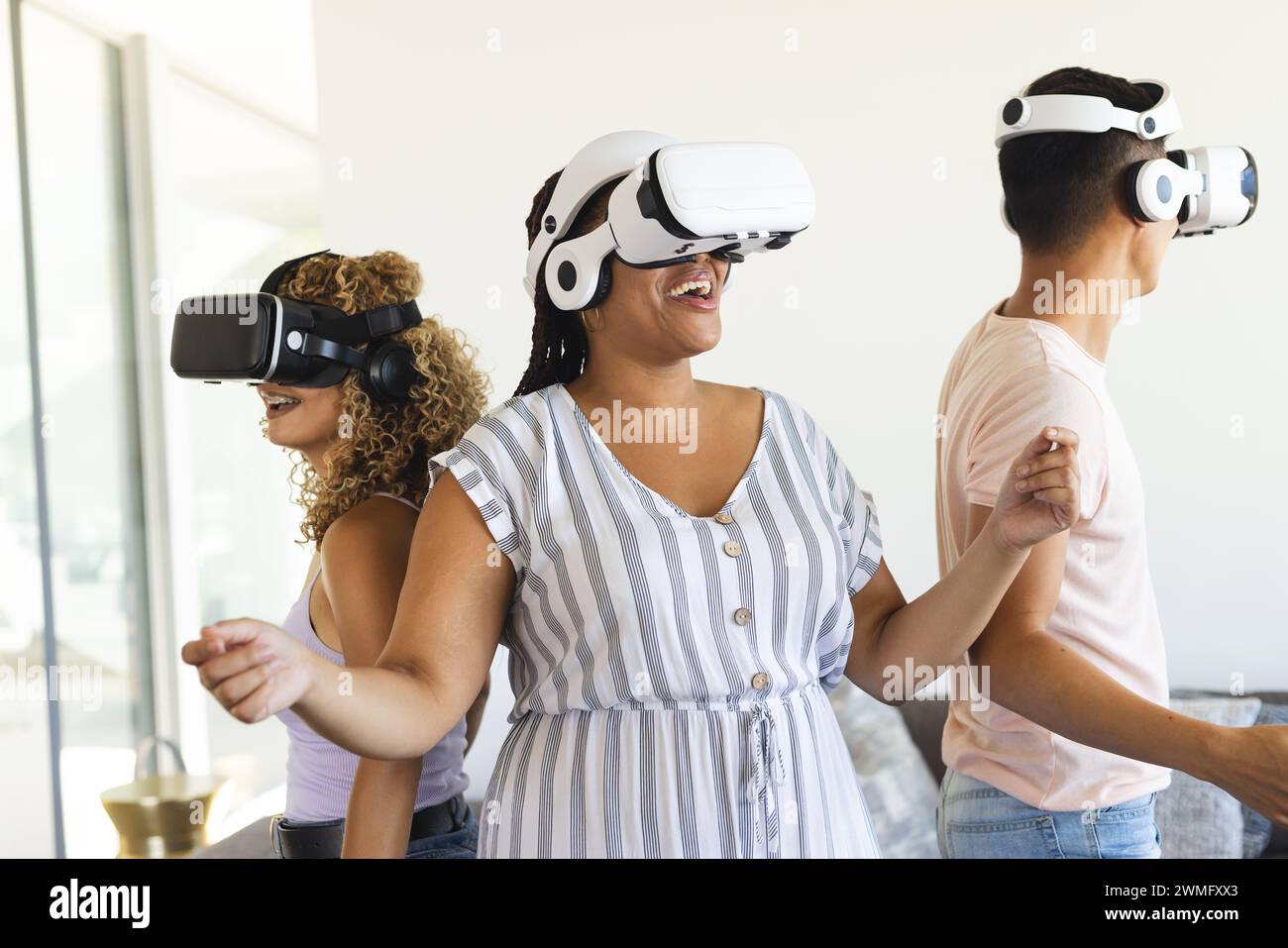Amici eterogenei si divertono con i giochi di realtà virtuale a casa Foto Stock