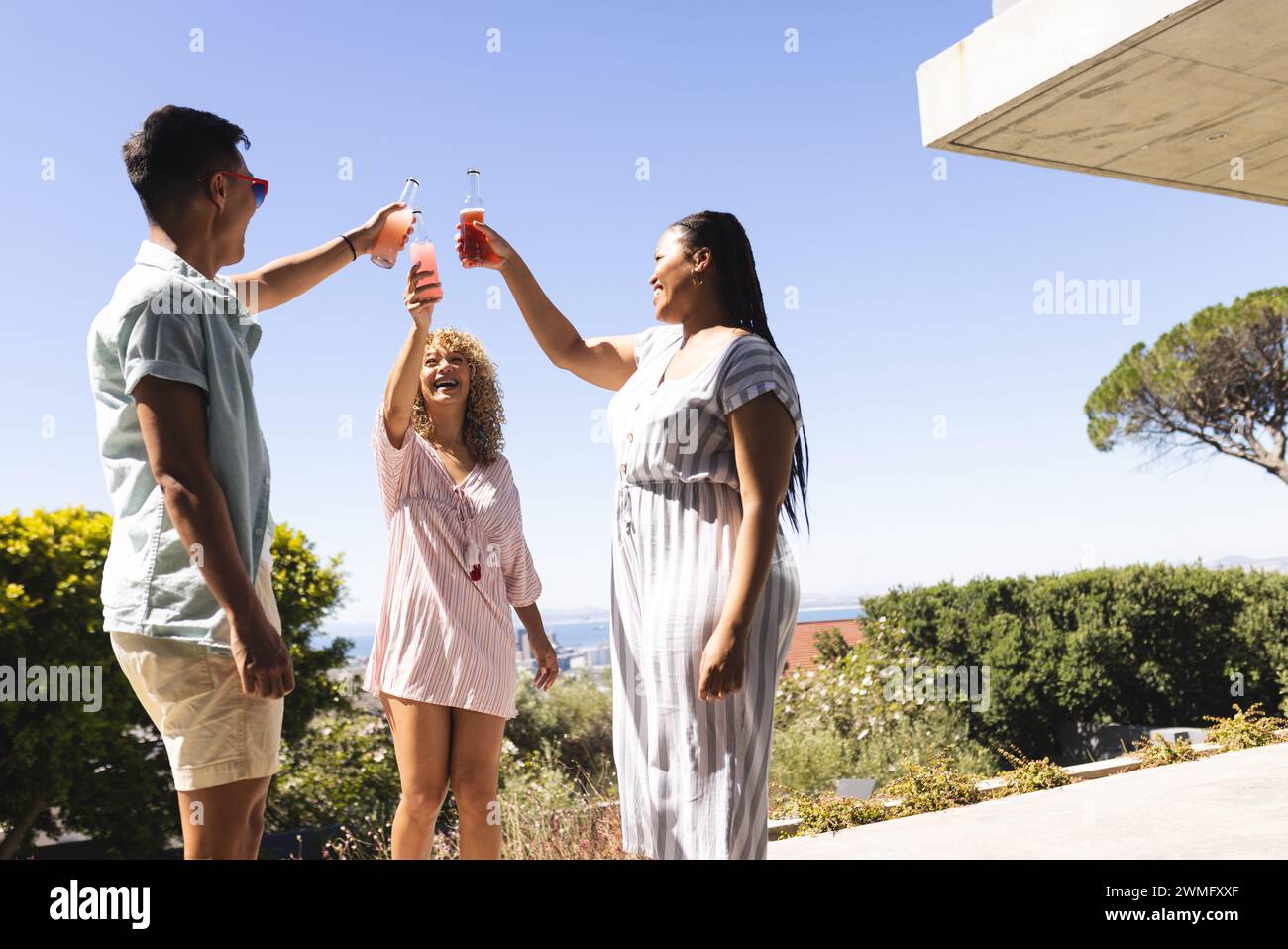 Giovani uomini asiatici e donne birazziali si godono bevande all'aperto Foto Stock