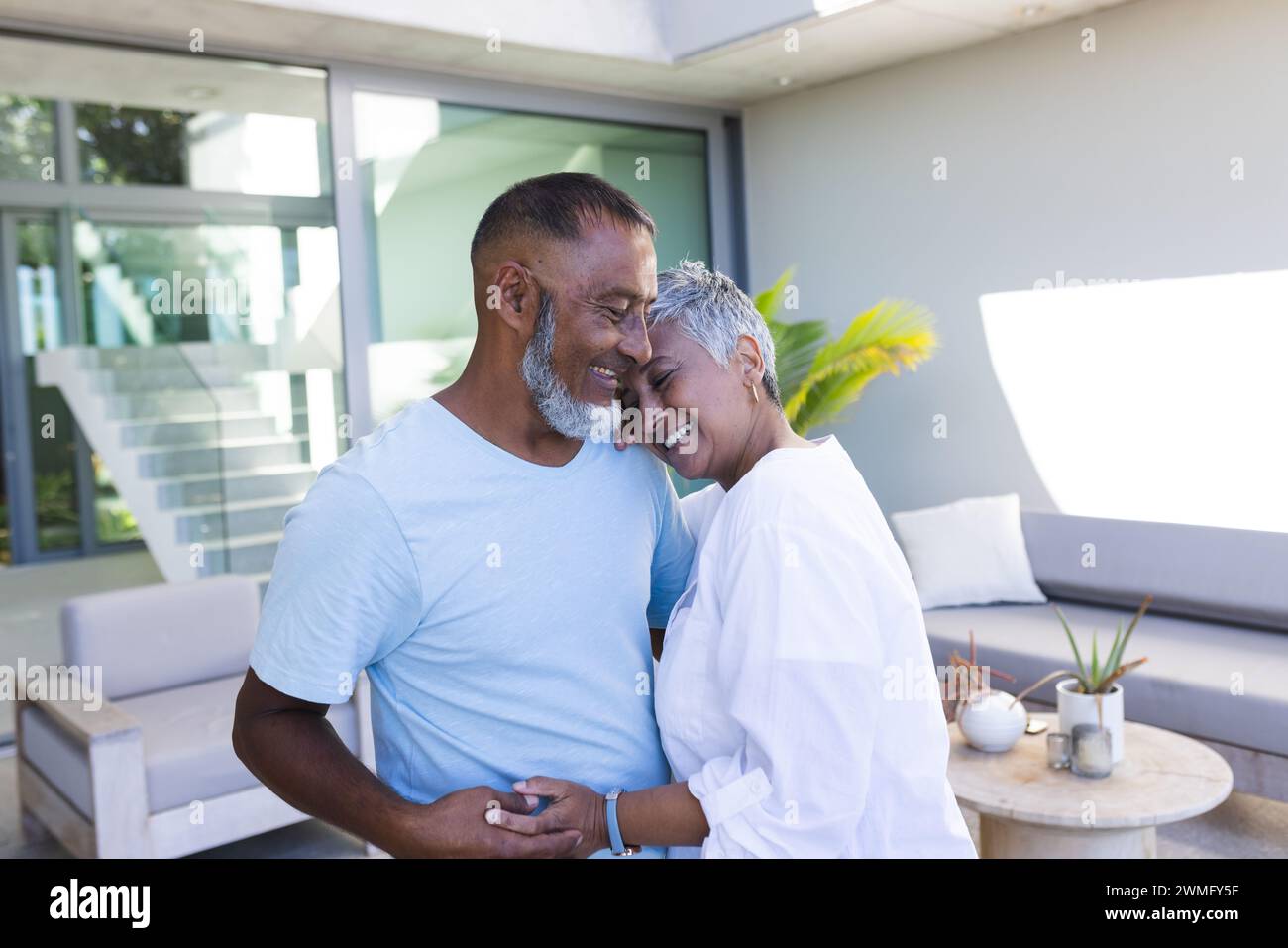 La coppia birazziale senior condivide un momento tenero a casa Foto Stock