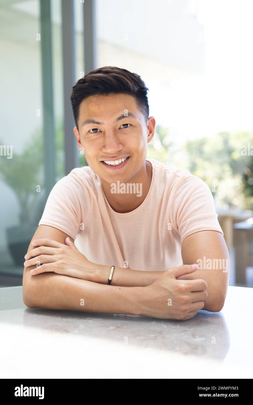 Il giovane asiatico sorride con fiducia in un ambiente luminoso Foto Stock