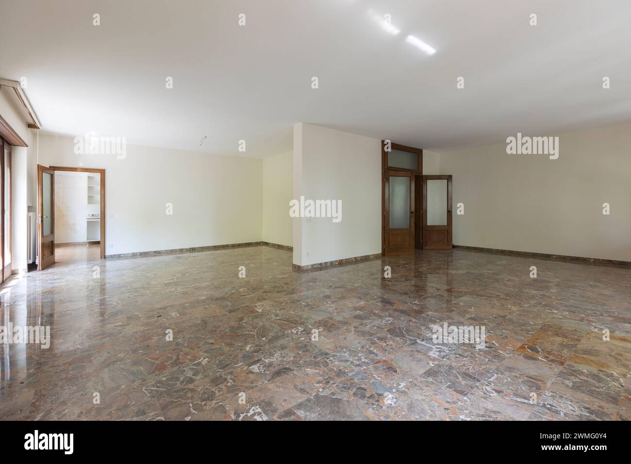 Grande soggiorno con pareti bianche e pavimento in marmo. Villa interna abbandonata d'epoca pronta per essere demolita. Nessuno dentro Foto Stock