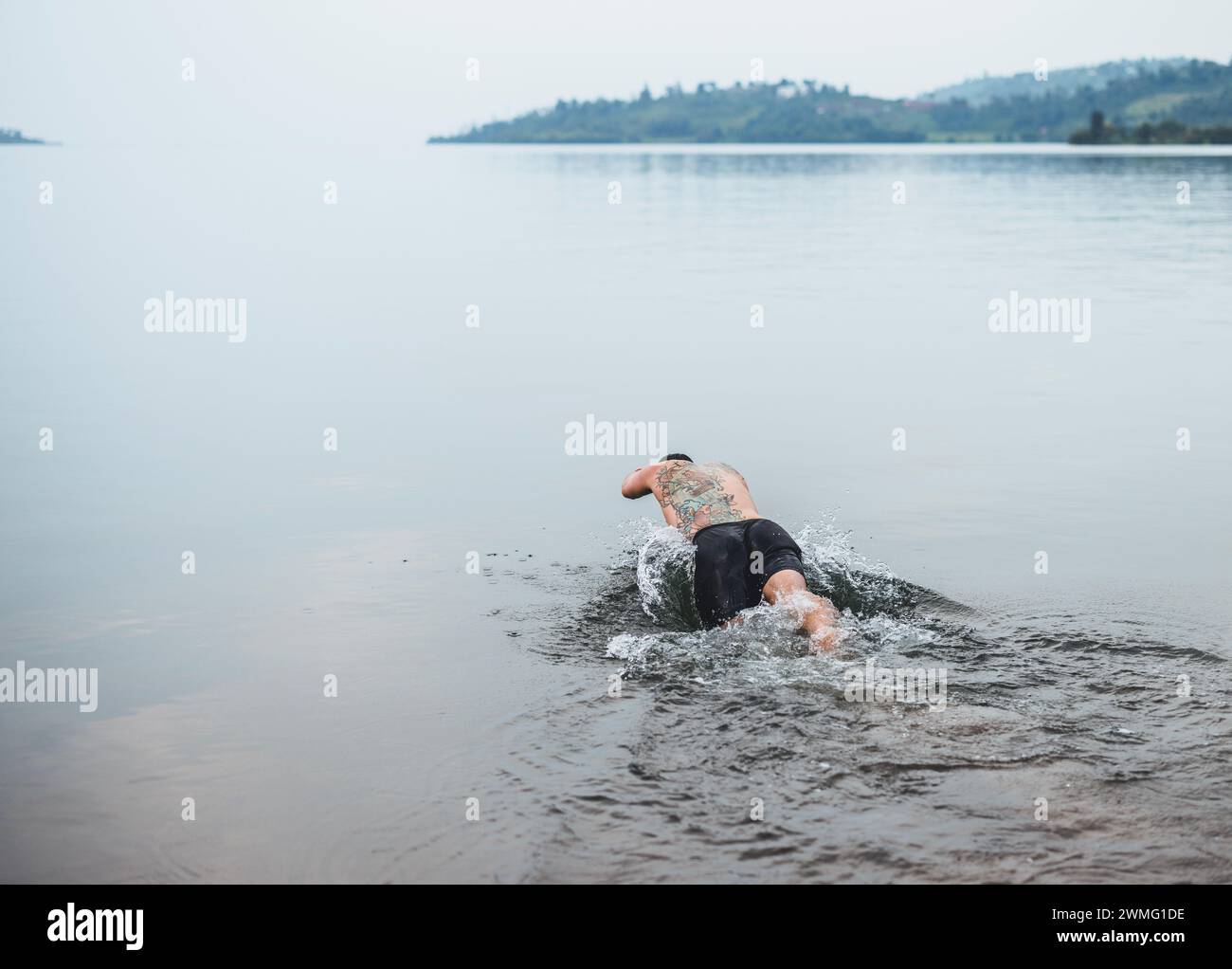 Un uomo con tatuaggi si tuffa nel lago Kivu, Ruanda Foto Stock