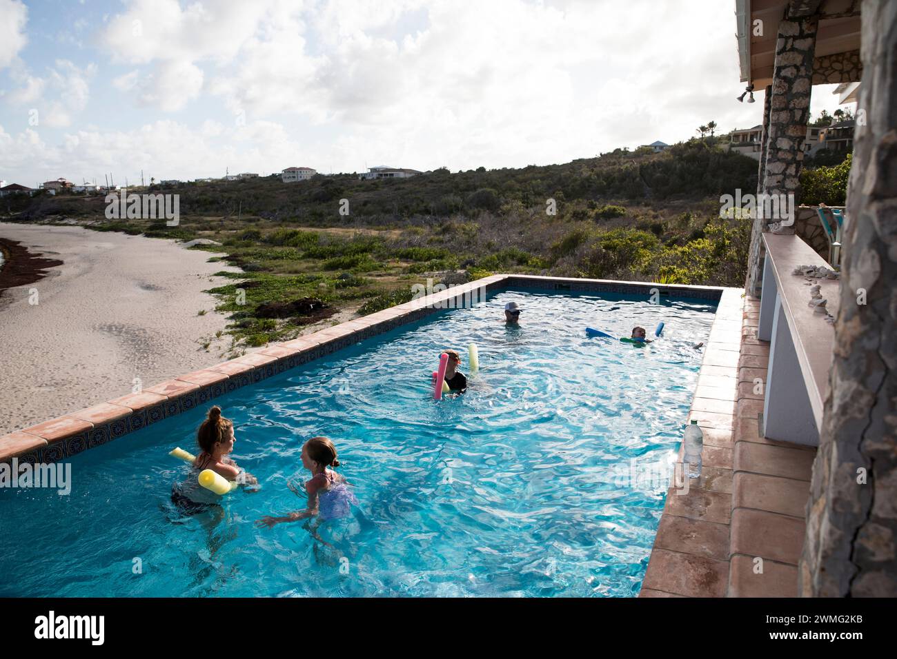 La famiglia nuota insieme nella piscina Infinity in vacanza ai Caraibi Foto Stock