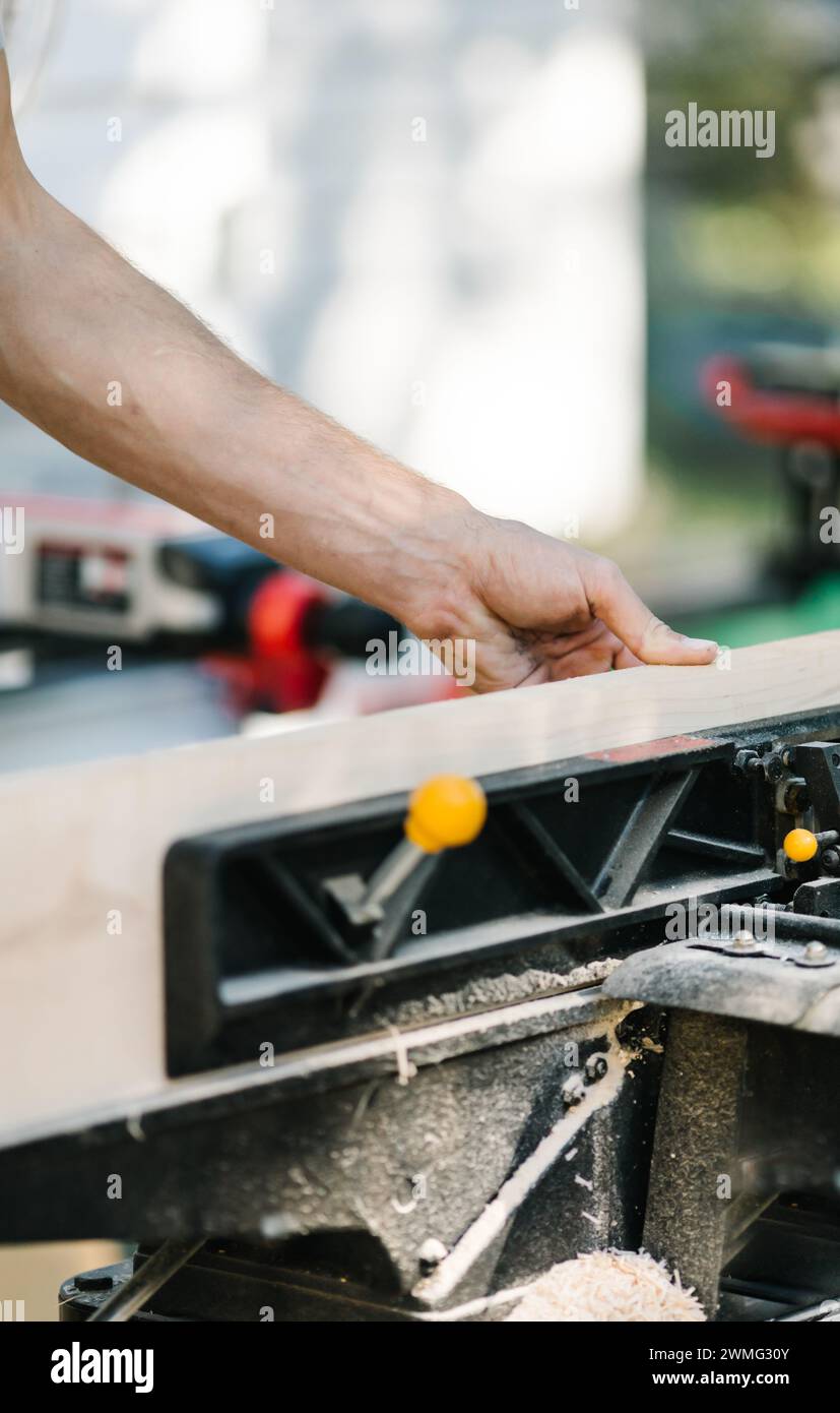 Falegname taglia con precisione il legno con una sega ad angolo. Foto Stock