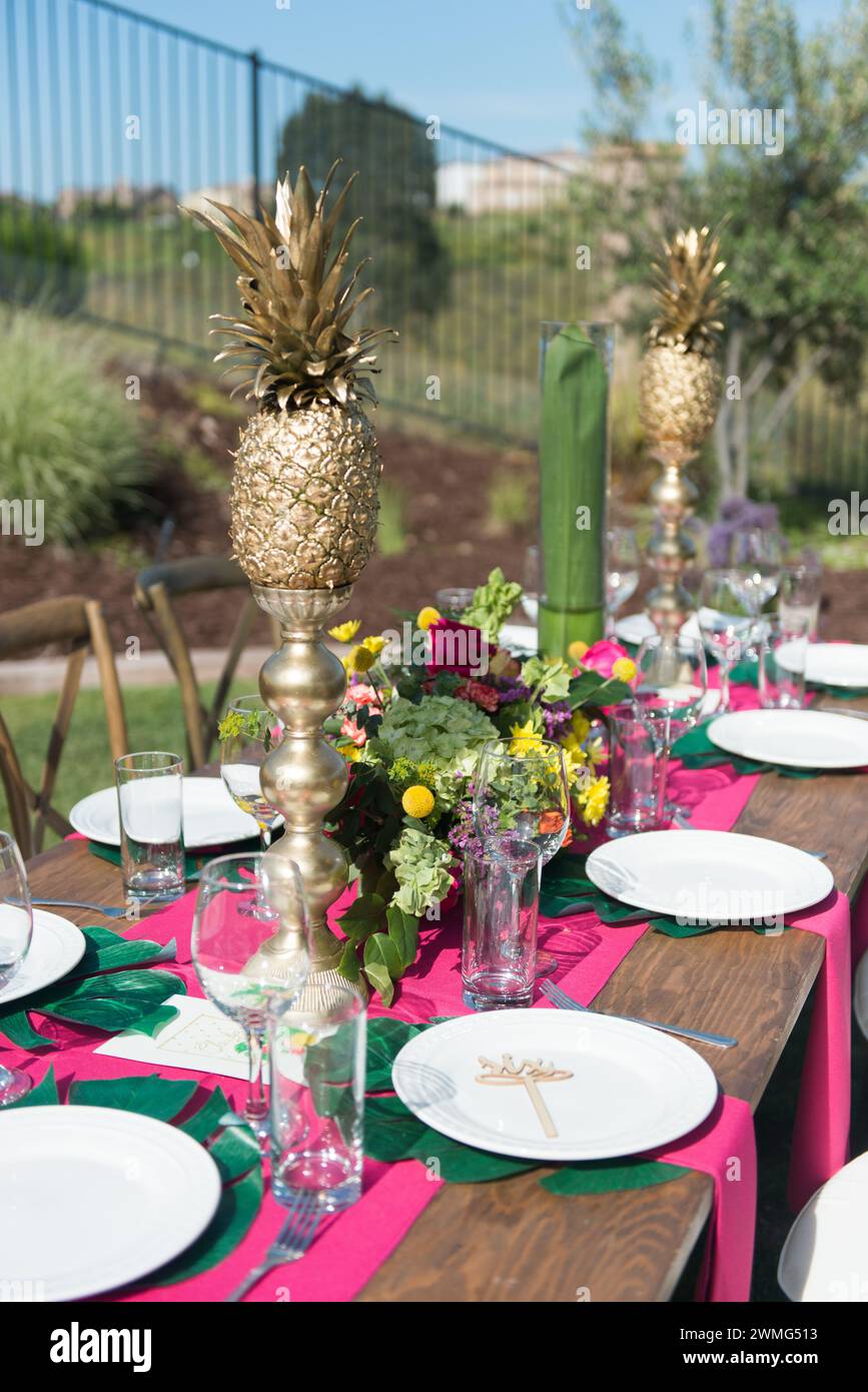 Tavolo a tema tropicale con ananas e fiori d'oro Foto Stock