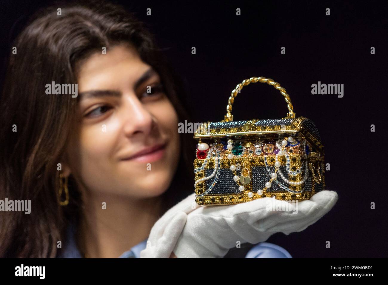Londra, Regno Unito. 26 febbraio 2024. Un membro dello staff con Judith Leiber: Pochette Gold "Sunken Treasure Chest", 2022, (circa £600 - £800) in anteprima dei prossimi saldi di Bonham per borse firmate e moda. Borse di lusso e design pronti all'uso saranno messi all'asta presso le gallerie Bonhams Knightsbridge il 28 febbraio. Crediti: Stephen Chung / Alamy Live News Foto Stock