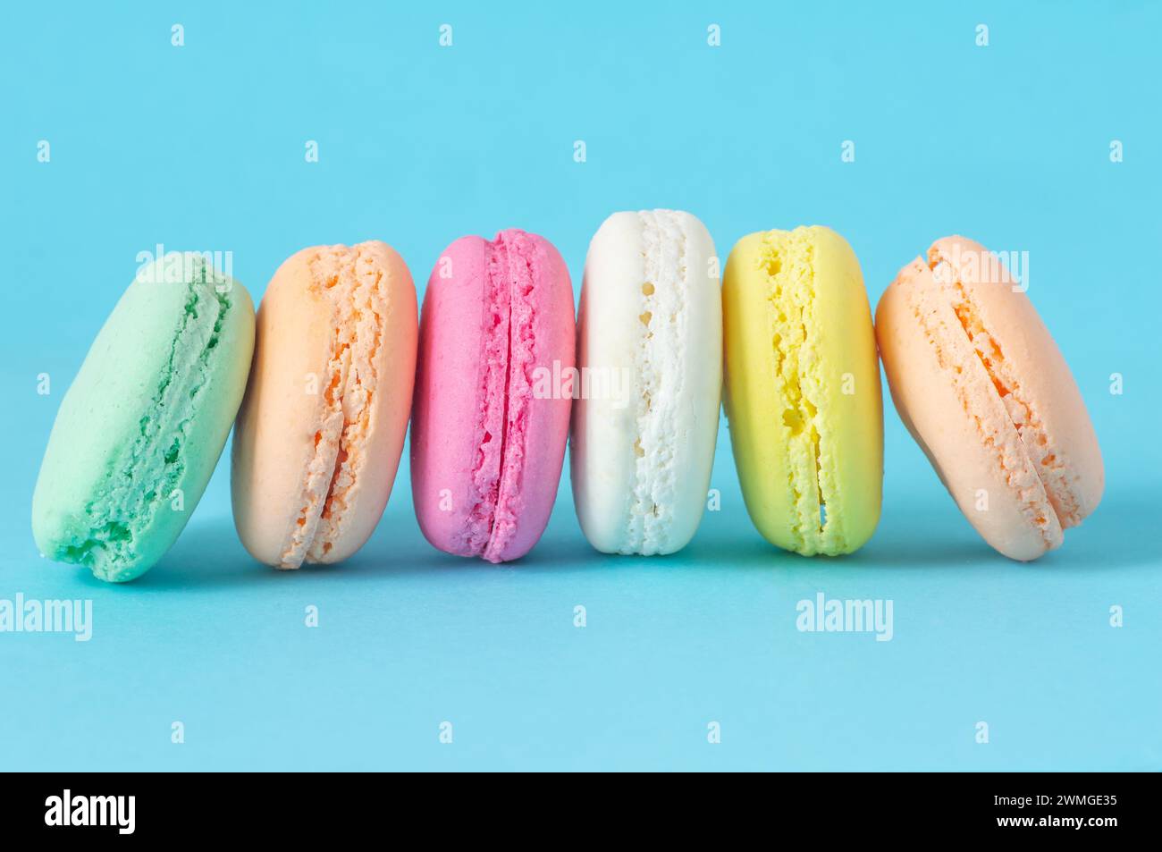 Dessert francese macaron colorati isolati su sfondo blu Foto Stock